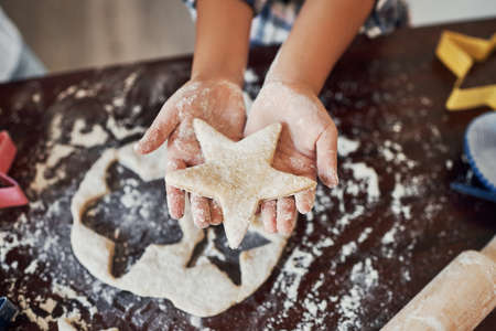 Dad calls me a star. an unrecognizable girl making star shaped cookies in the kitchen at home.の写真素材