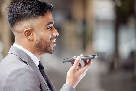 Voice notes are easier than texting. a handsome young businessman standing in the city and using his cellphone.の写真素材