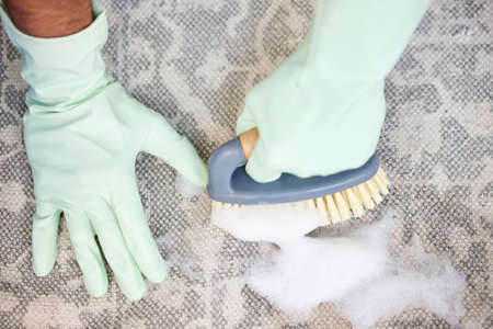 Put some effort into it. a young man scrubbing the floor at home.の写真素材