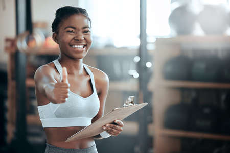 Thats what I like see. Portrait of a young beautiful woman using a digital tablet and showing the thumbs up at the gym.の写真素材
