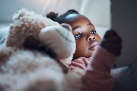 I hope no one disturbs me. a little girl using her digital tablet in her bedroom.の写真素材