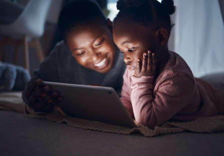 And then they lived happily ever after. a mother reading bedtime stories with her daughter on a digital tablet.の写真素材