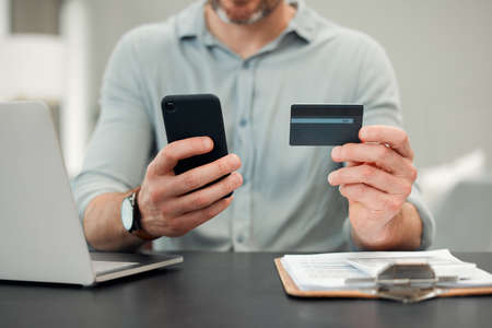 Paying bills has never been easier. an unrecognizable man paying bills while sitting at his desk at home.の写真素材