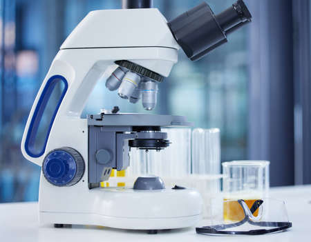 A lot of dedication goes into making new discoveries. a microscope and goggles on a table in a...