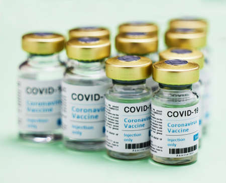 Lets kick covid to the curb. Studio shot of vaccine tubes against a green background.