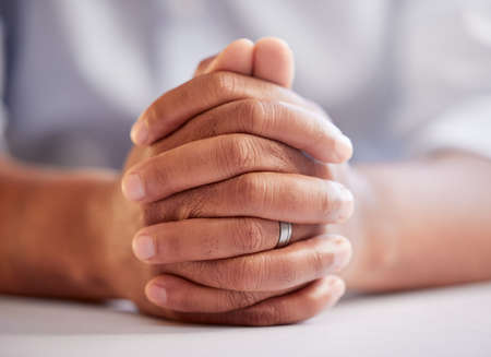 A man of faith. an unrecognizable man sitting down with his hands clasped in prayer.の写真素材