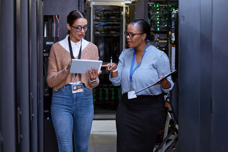 Lets check the connectivity. two attractive young female computer programmers working together in a server room.の写真素材