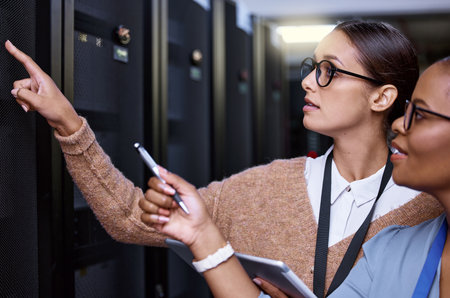 This one. two attractive young female computer programmers working together in a server room.