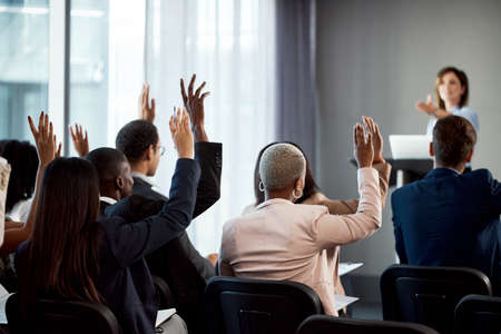 Fill us with your vision. Rearview shot of a group of businesspeople raising their hands during a conference.の写真素材