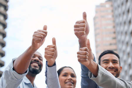 Giving ourselves a pat on the back. a group of businesspeople giving the thumbs up.の写真素材