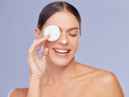 Start somewhere. a beautiful young woman using a cotton pad to clean her face against a purple...