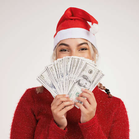 The best Christmas gift. Studio shot of a young woman posing with money against a grey background.の写真素材