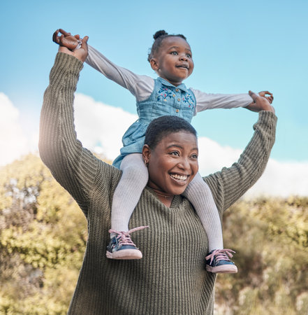Its all smiles when theyre at the park. a mother carrying her daughter on her shoulders outdoors.の写真素材