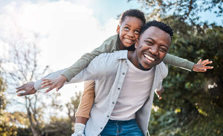 Make sure youre always making memories with your kids. Portrait of a father giving his son a piggyback ride outdoors.の写真素材