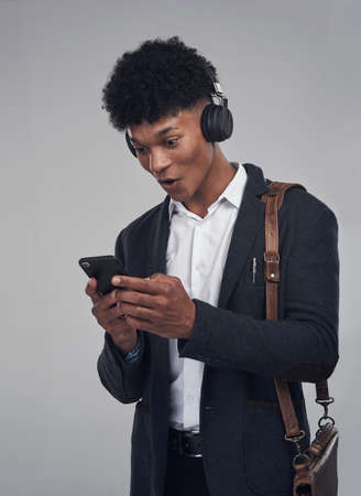 Turn it up and let the music work its magic. Studio shot of a young businessman using a smartphone...