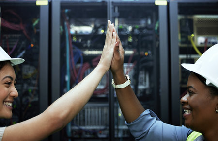 Problem solved. two attractive female programmers high fiving in a server room.の写真素材