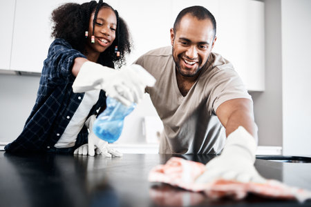 No mess is too much for us. a young girl helping her father clean the kitchen counter at home.の写真素材