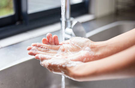 Hygiene is a priority to me. an unrecognizable woman washing her hands in the sink at home.の写真素材