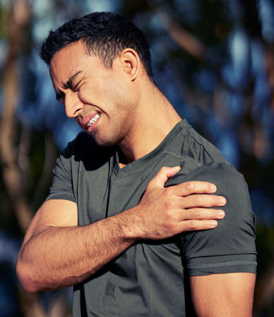 An injury can limit your movement and cut your strength. a sporty young man holding his shoulder in...