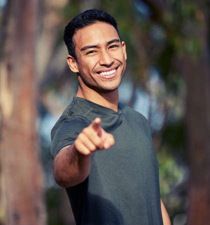 I challenge you to get your body moving. Portrait of a sporty young man pointing outdoors.の写真素材