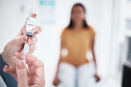 The time to take action is now. a doctor giving a patient an injection at a clinic.の写真素材