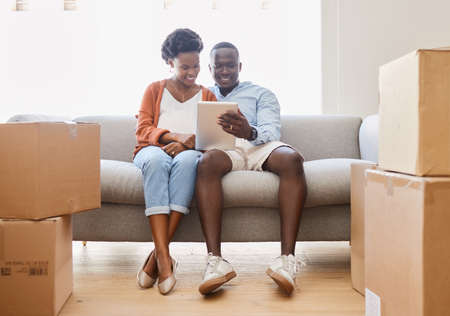 Home is wherever we are together. a young couple sitting on the couch while using a digital tablet...
