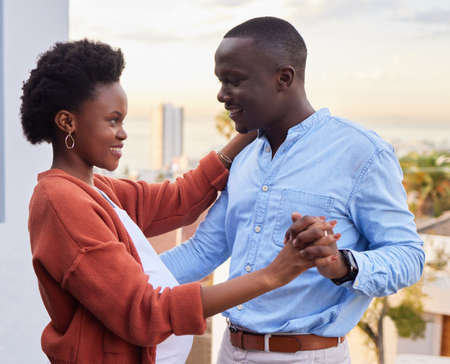 Dancing into this next chapter in life with you. a happy young couple standing together and dancing on their balcony at home.の写真素材