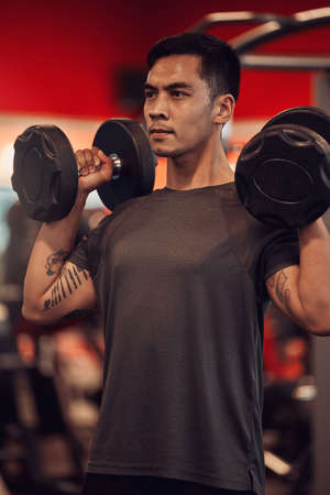 No excuses get that workout in. a young man lifting weights at the gym.の写真素材