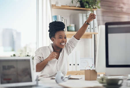 I love getting good news. a young business celebrating by cheering in her office.