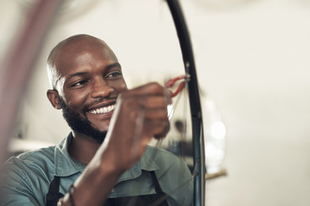 This wont be breaking again. a handsome young man standing alone in his shop and repairing a bicycle wheel.の写真素材