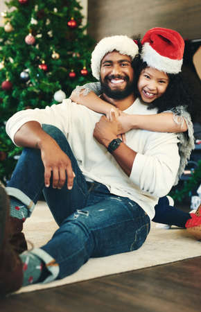 Santa is great but Dadd got my heart. Portrait of a happy young father and daughter celebrating Christmas at home.の写真素材