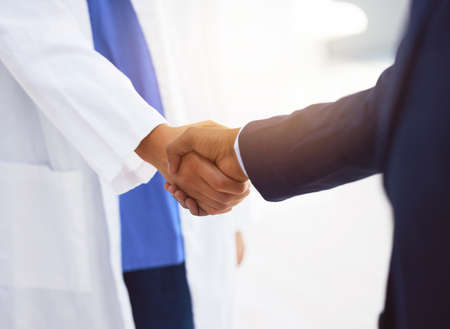 Im your answer, if you move me, Im your dancer. a doctor shaking hands with a businessman in a hospital.の写真素材