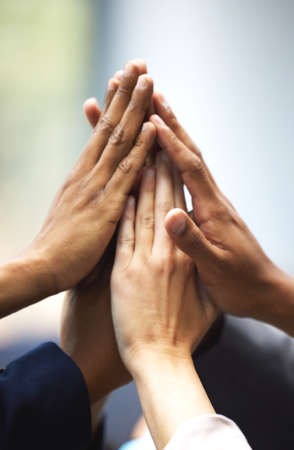 We work better as a team. a group of unrecognizable businesspeople holding up their hands for a high five in an office.の写真素材