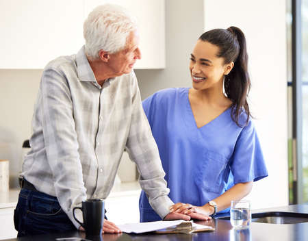 This paperwork will secure your future. a nurse going over paperwork with her senior patient.の写真素材