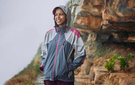 When the mountains call, you cant help but to answer. a woman wearing her rain jacket while out...