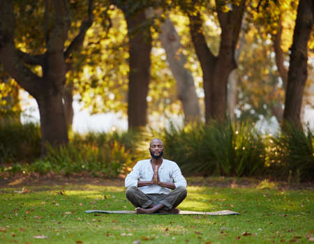 The perfect place to find your center. Full length shot of a handsome young man meditating while...