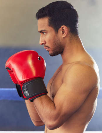 Form and focus. a handsome young male boxer standing with his guard up during a fight in the ring.の写真素材