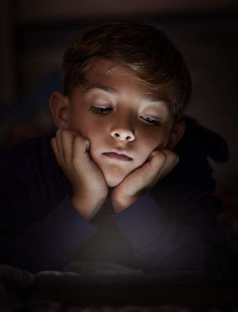 Dare to see the world as a child, magical and true. adorable little boy using a digital tablet at...