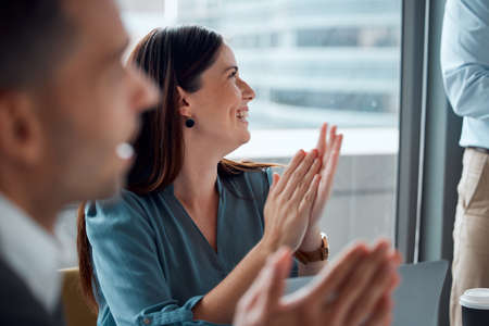 Theyre always doing great work together. a young businesswoman applauding with her colleagues during...