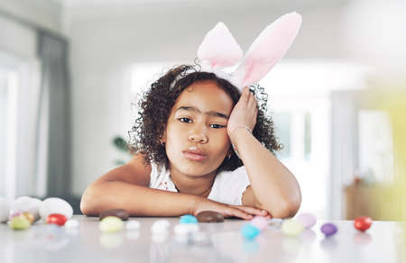 One grumpy little easter bunny. a unhappy girl sitting at home.の写真素材