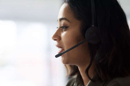 One of our agents will be with you shortly... a young businesswoman wearing a headset while working in a call centre.の写真素材