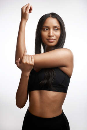 Stretching promotes muscle flexibility. Studio shot of a sporty young woman stretching her arms...