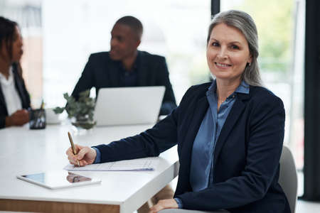 A great plan to really help drive growth. a mature businesswoman writing notes during a meeting in a...
