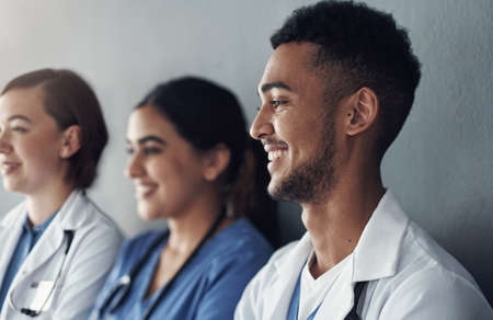 Always remember the privilege it is to be a physician. a group of doctors standing against a grey background at work.の写真素材