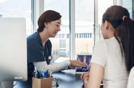 This is what it looks like. a young female doctor showing a patient a digital x-ray in an office.
