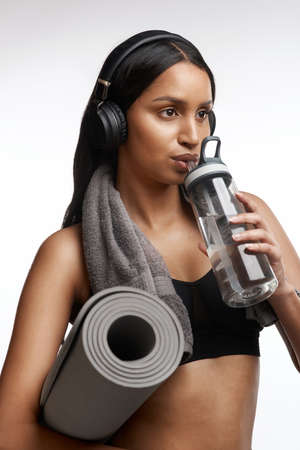 Sip water at regular intervals while exercising. Studio shot of a sporty young woman drinking water...