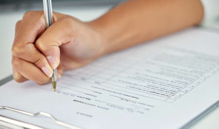 Taking a quick survey. an unrecognizable businesswoman filling out a questionnaire while sitting in...