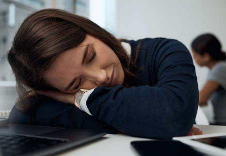 Just a little break. a young businesswoman taking a nap at her desk in her office.の写真素材