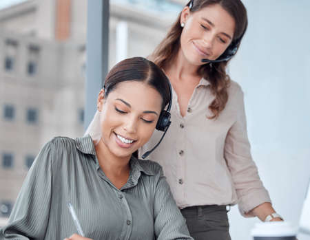 Ill make a note of that. two businesswoman working together in a call centre office.