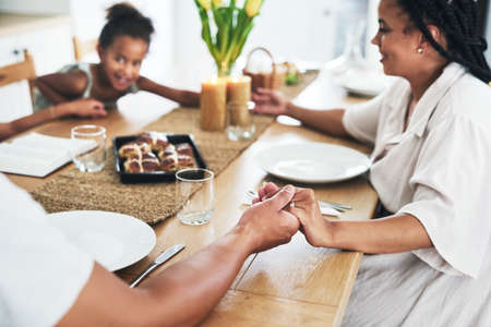 Blessing the meal that has been prepared. an unrecognizable family holding hands during prayer time at home.の写真素材